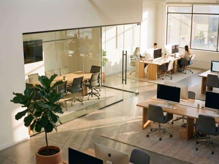 Modernt kontorslandskap med glasomgärdat privatkontor, ergonomiska möbler och naturligt ljus genom fönster